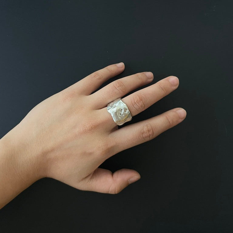 Hand wearing a decorative ring on a dark background